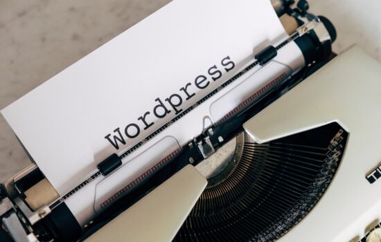 Eine alte Schreibmaschine in welche ein weißes Blatt Papier eingespannt ist. Darauf steht Wordpress.